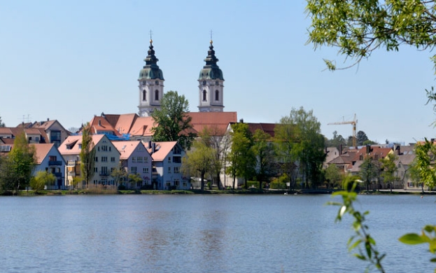 Foto von der Stadt Bad Waldsee, auf der sowohl die Kirche und Häuser als auch der wunderschöne See zu sehen sind