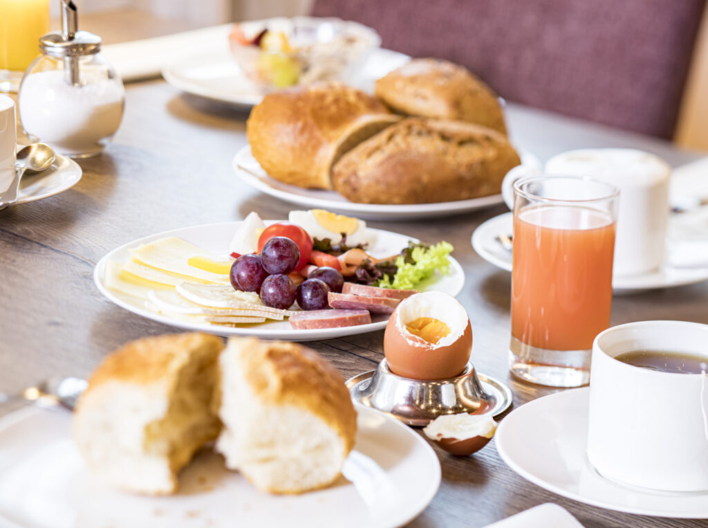 a balanced breakfast on a table with sausage,cheese, eggs, juice and coffee